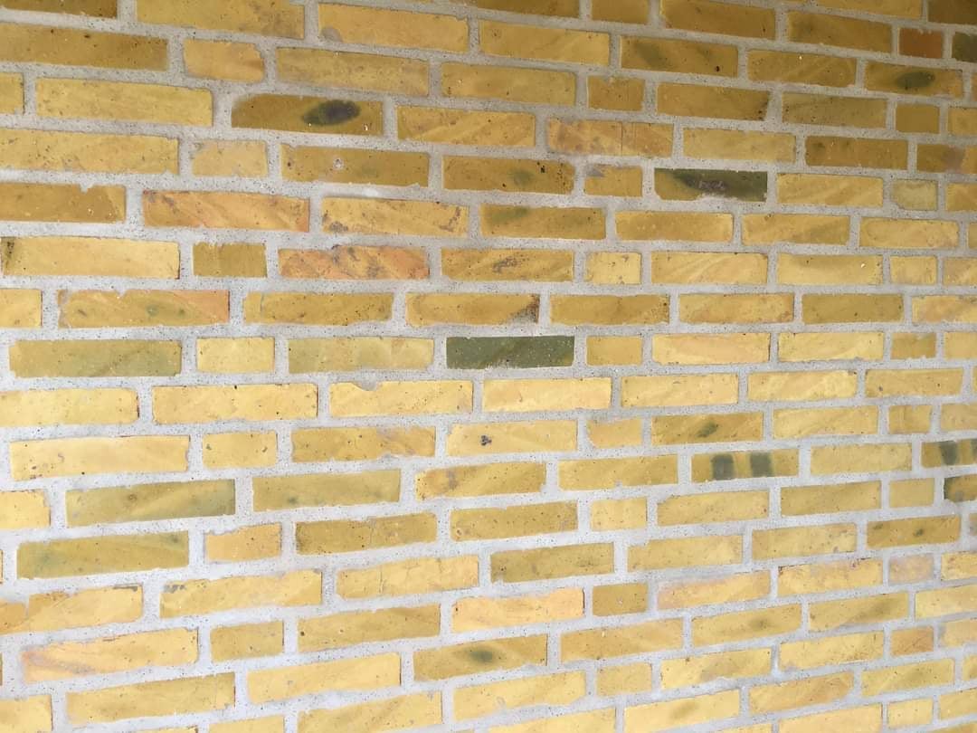 Close-up of a tan and cream colored brick wall with white mortar joints in a running bond pattern.