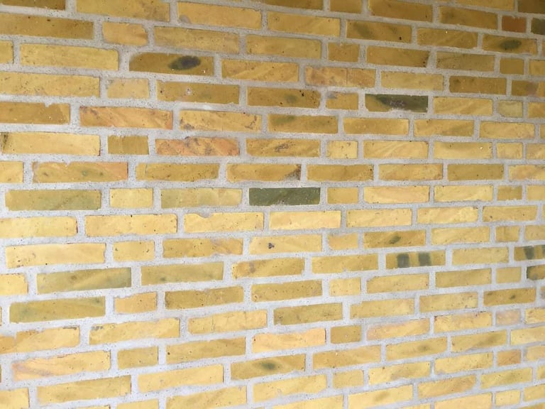 Close-up of a tan and cream colored brick wall with white mortar joints in a running bond pattern.